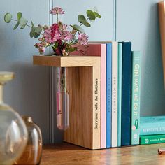 a vase with flowers and books on a shelf