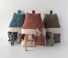 three small stuffed animals sitting next to each other in front of a house made out of knitted material