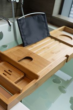 a wooden tray with a knife and cutting board on it in front of a bathtub