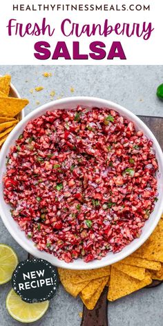 fresh cranberry salsa in a white bowl surrounded by tortilla chips and limes