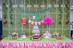 a table topped with cake and cupcakes next to a wall covered in grass