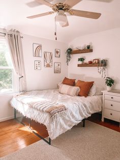 a bedroom with a bed, dresser and ceiling fan in the corner next to a window