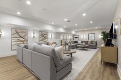 a living room filled with lots of furniture next to a wall mounted tv on top of a hard wood floor