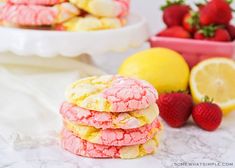 a stack of pink and yellow cookies next to some strawberries