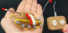 a hand holding a small wooden toy tank with two magnets attached to it, and an electronic device in the palm of someone's hand