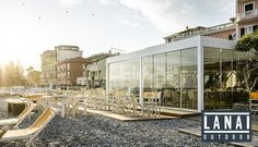 an outdoor dining area with tables and chairs in front of a building on the beach