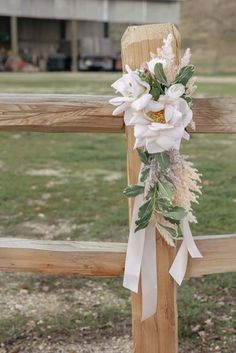 a cross decorated with flowers and greenery in front of a wooden fence at a park