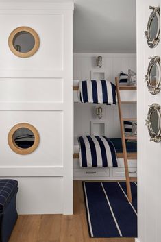 a bunk bed room with blue and white striped bedspread, wooden ladder and round mirrors on the wall