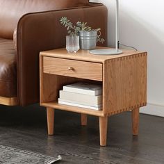 a wooden table with two plants on it and a leather couch in the back ground