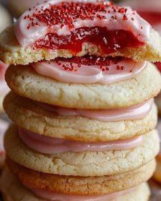 a stack of cookies with pink icing and sprinkles on top,