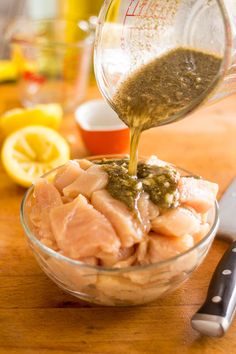 someone pouring dressing into a glass bowl filled with fish