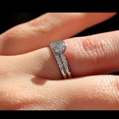 a woman's hand with a diamond ring on top of her finger and an engagement band