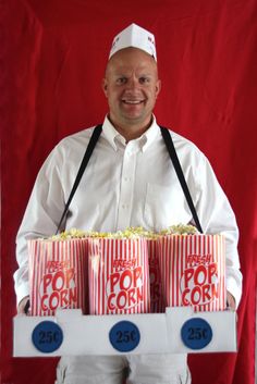 a man in white shirt holding three boxes of popcorn