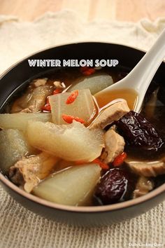 a bowl of soup with meat and fruit in it on a white table cloth next to a spoon