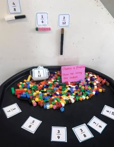 a black table topped with lots of legos next to numbers and a pink sign