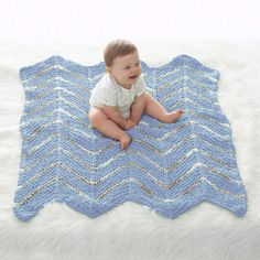 a baby is sitting on a blue crocheted blanket