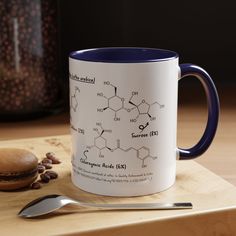 a blue and white coffee mug sitting on top of a wooden table next to a spoon