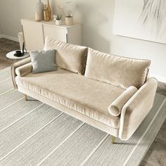 a beige couch sitting on top of a rug in a living room