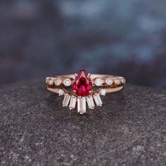 a close up of a ring with a red stone in the middle and white stones around it