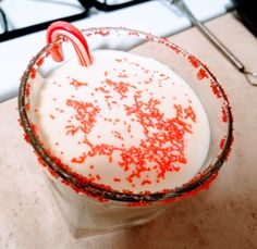 a drink with candy canes and sprinkles in a glass on the counter