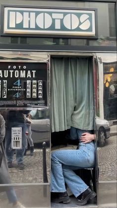 a man sitting in an atm machine on the side of the street with his head down