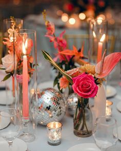 a table topped with lots of vases filled with flowers and lit candles next to each other