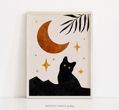 a black cat sitting on top of a table under a moon and palm leaf print