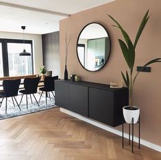 a living room with a large mirror and dining table in the corner, next to a potted plant