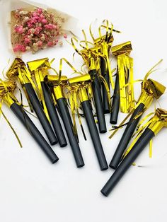 black and gold confetti sticks with streamers on white tablecloth next to flowers