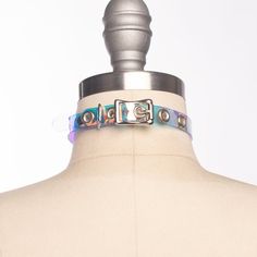 Classic choker collar in iridescent, holographic vinyl layered over PVC. An aurora borealis chandelier crystal point adorns the center o-ring. Fit is adjustable with buckle. Holes are reinforced with grommets.This is the mini version - slightly slimmer with a smaller crystal for a more delicate look!Collar is 1/2" wide, with a 1" crystal point.SMALL/MEDIUM (11-13")MEDIUM/LARGE (13-15")LARGE/X-LARGE (15-17")Custom sizing available.  All pieces are MADE TO ORDER, standard sizes S/M-L/XL.  If your Multicolor Punk Jewelry For Parties, Punk Multicolor Party Jewelry, Adjustable Multicolor Choker For Parties, Adjustable Multicolor Party Choker, Adjustable Silver Choker For Cosplay, Adjustable Iridescent Necklace For Festivals, Elegant Iridescent Adjustable Necklace, Adjustable Rave Style Choker, Adjustable Rave Choker For Festival