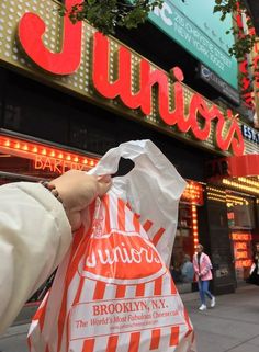 a person is holding up a bag in front of a store that has neon signs on it