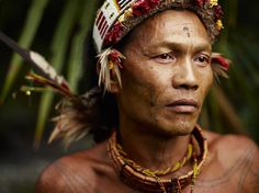 a native american man with tattoos and feathers on his head is staring at the camera