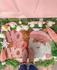 a person standing in front of a christmas rug with santa clause and flowers on it