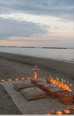 a table set up on the beach with candles