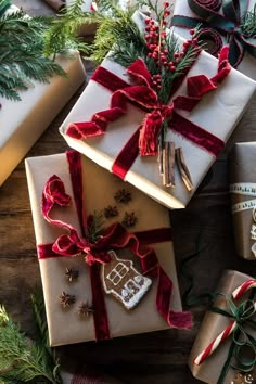 presents wrapped in white paper and tied with red ribbon on top of wooden table next to christmas decorations