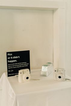 two cameras sitting on top of a table next to a sign that says pics didn't happen