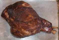 a large piece of meat sitting on top of a metal pan next to a wooden spoon