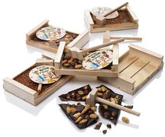 four wooden boxes filled with different types of nuts and chocolates, one is open to show the contents