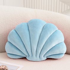 a blue shell shaped pillow sitting on top of a couch