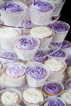 cupcakes with purple frosting are stacked on top of each other in lace doily