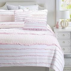 a bed with pink and white comforters in a bedroom