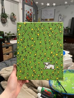 a person holding up a green notebook with yellow flowers on it