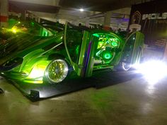 a green car with lights on it's side in a parking lot at night