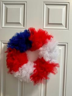 a red, white and blue wreath hanging on a door