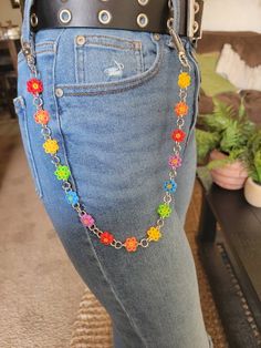 a woman is wearing a black belt with colorful beads and chains on her waist as she stands in front of a couch