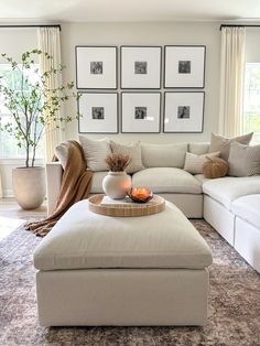 a living room filled with white furniture and pictures on the wall above it's coffee table