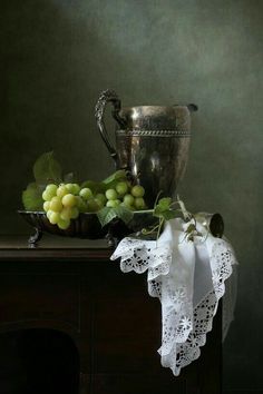 grapes and a silver pitcher on a table