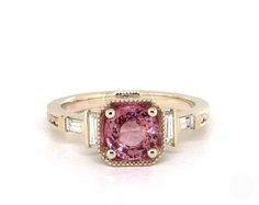 a pink diamond ring with three baguets on the band and two diamonds around it