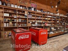 two coca - cola coolers are sitting in the middle of a room full of shelves