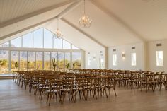 an empty room with chairs and chandeliers in front of large windows overlooking mountains